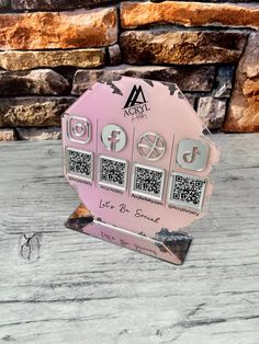 a pink plaque with qr code on it sitting on top of a wooden table