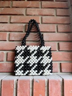 a black and white beaded purse hanging on a brick wall