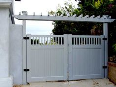 a white gate with a trellis over it