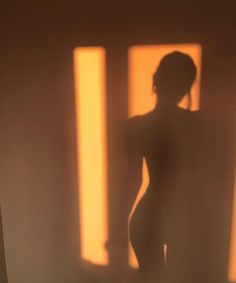 a woman standing in front of a window with the shadow of her body on it