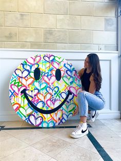 a woman sitting on the floor next to a large smiley face sign