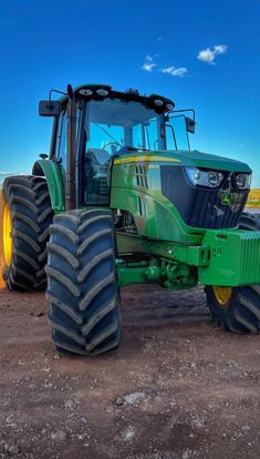 a green tractor parked on top of a dirt field