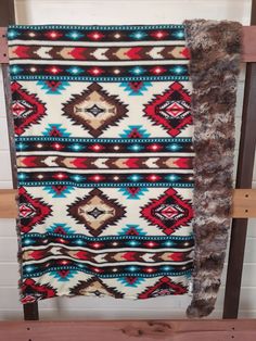 an old blanket hanging on a wooden rack in a room with white brick walls and wood flooring