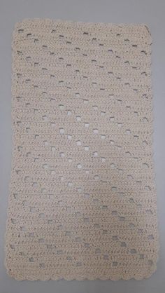 a white crocheted square with holes in the middle on a gray background,