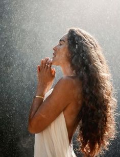 a woman standing in the rain with her hands together