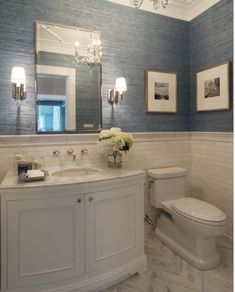 a white toilet sitting next to a sink in a bathroom under a chandelier