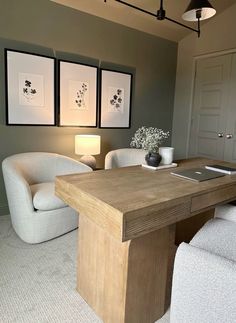 a living room with two chairs, a table and pictures on the wall above it