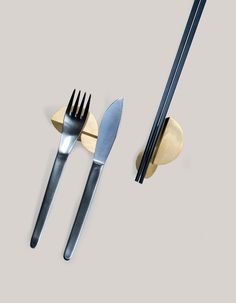 three forks, two spoons and one knife on a gray surface with gold accents