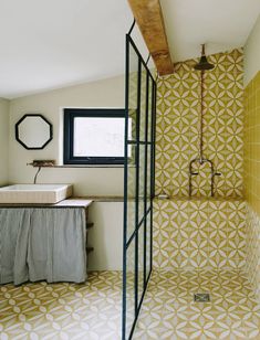 a bathroom with yellow and white tiles on the floor, shower stall and sink area