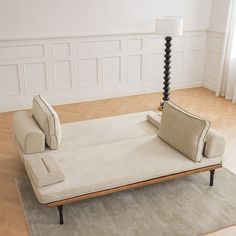 a white couch sitting on top of a hard wood floor next to a light colored rug