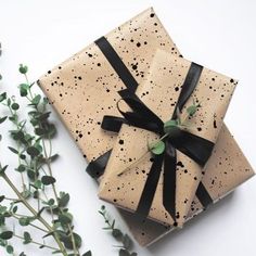 a present wrapped in brown paper and tied with black ribbon sitting next to some flowers