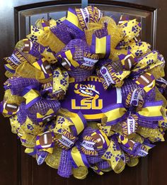 a purple and yellow wreath with lsu footballs on the front, hanging from a wooden door