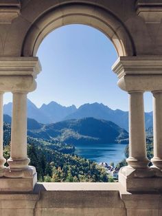 an arched window overlooking a lake and mountains