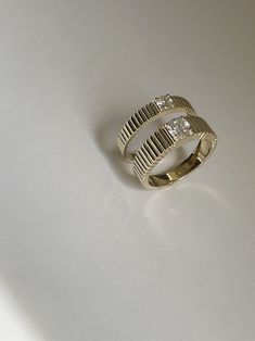 a gold ring with two diamonds sitting on a white surface