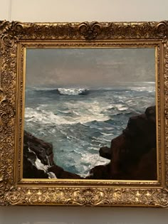 a painting hanging on the wall with waves coming in from the ocean and rocks below