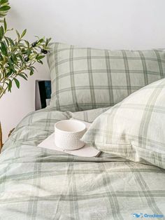 a white bowl sitting on top of a bed next to pillows and a potted plant