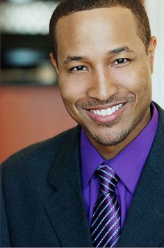 a man in a suit and tie smiling at the camera