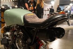 a green and black motorcycle on display in a showroom with people looking at it