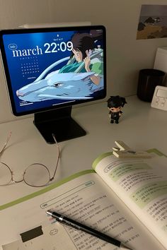 a desktop computer monitor sitting on top of a desk next to a book and glasses