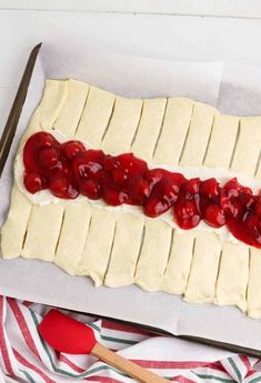 an uncooked pastry with cream and cherries on it, ready to be baked