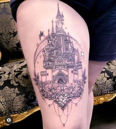 the back of a woman's thigh with a castle tattoo on her left side