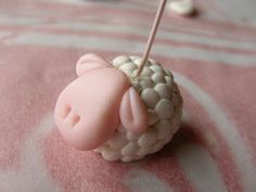 a pink and white sheep pin cushion with pins in it's ear sitting on a table