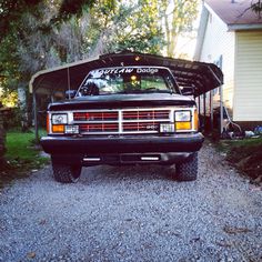 a truck parked in front of a house with a canopy over it's head