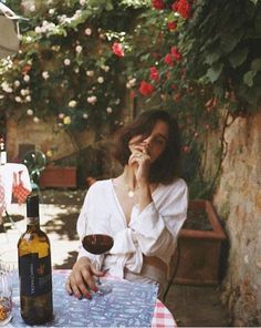 a woman sitting at a table with a glass of wine