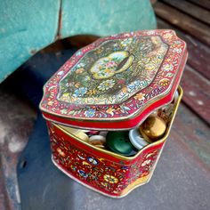 an ornately decorated tin box sitting on top of a wooden bench