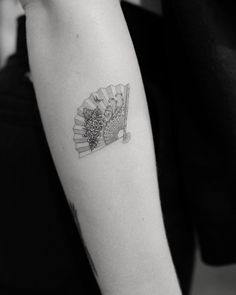 a black and white photo of a woman's arm with a tattoo on it