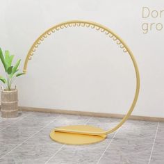 a plant sits on the floor in front of a white wall and a yellow stand