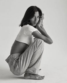 a black and white photo of a woman sitting on the ground with her legs crossed