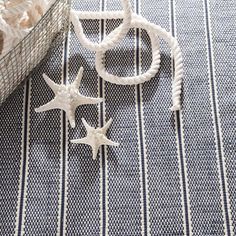 three white starfishs on a blue and white striped tablecloth next to a basket full of seashells