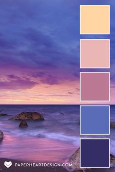 the ocean is full of purple and blue hues, with rocks in the foreground