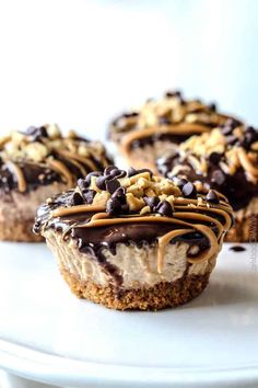 three desserts with chocolate and nuts on top are sitting on a white countertop