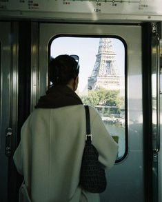 a woman is looking out the window of a train at the eiffel tower