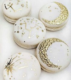 four decorated macaroons with gold glitters on them and the moon in the middle