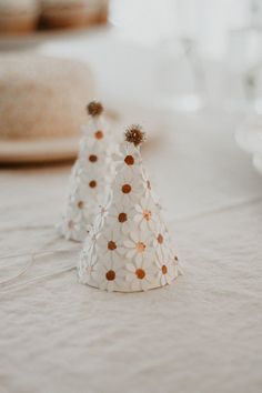 two small white paper hats sitting on top of a table next to plates and glasses