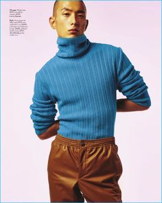 a man in a blue turtle neck sweater and brown pants poses for a magazine cover