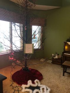 a decorated christmas tree in the corner of a living room with a piano and window