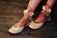 a woman's feet with hennap and flowers on their ankles, sitting on a wooden floor