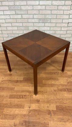 a wooden table sitting on top of a hard wood floor next to a brick wall