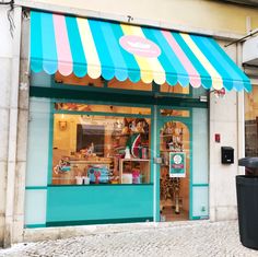 a store front with an awning over the door and trash can on the sidewalk