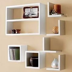 several white shelves are arranged on the wall with books and vases in front of them