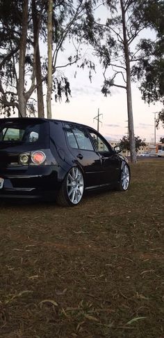 a black car parked in front of some trees