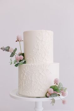 a white wedding cake with pink flowers and greenery