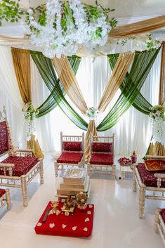 a room filled with lots of red and white furniture next to a window covered in drapes