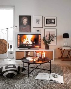 a living room with pictures on the wall and candles in front of it, next to a round coffee table