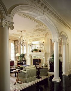 an elegant living room with columns and chandeliers