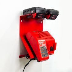 an electrical device mounted to the side of a wall with two red batteries attached to it